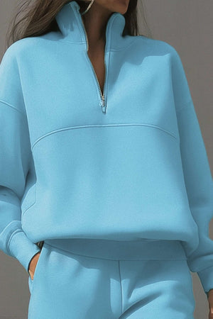 Light blue cotton blend tracksuit with high collar and zip neckline, featuring long sleeves and relaxed fit.