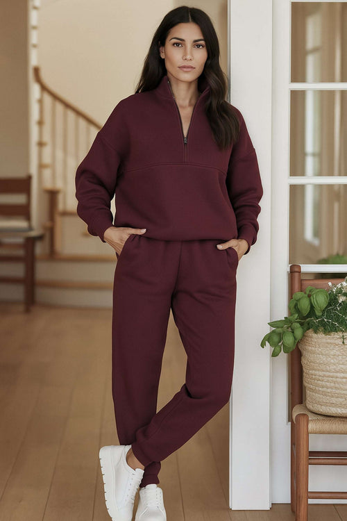 Woman wearing burgundy cotton blend tracksuit with zip neckline and relaxed fit in modern home interior