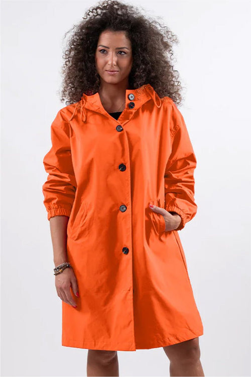 Woman wearing trendy oversized orange Rain Couture Windbreaker jacket, water-resistant and stylish for rainy weather