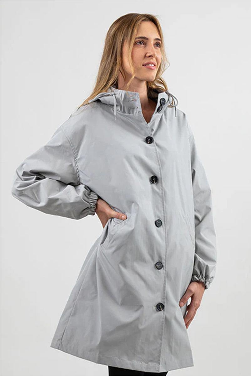 Woman wearing a trendy oversized light grey Rain Couture Windbreaker water-resistant jacket with hood and button closure
