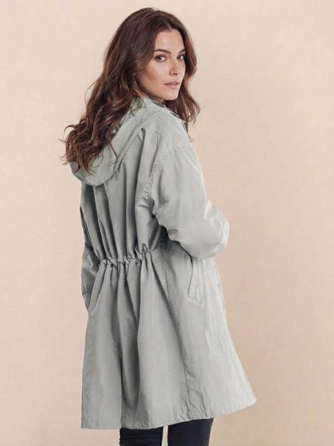 Woman wearing oversized Rain Couture Windbreaker in light grey, water-resistant fabric with adjustable hood and drawstring waist.