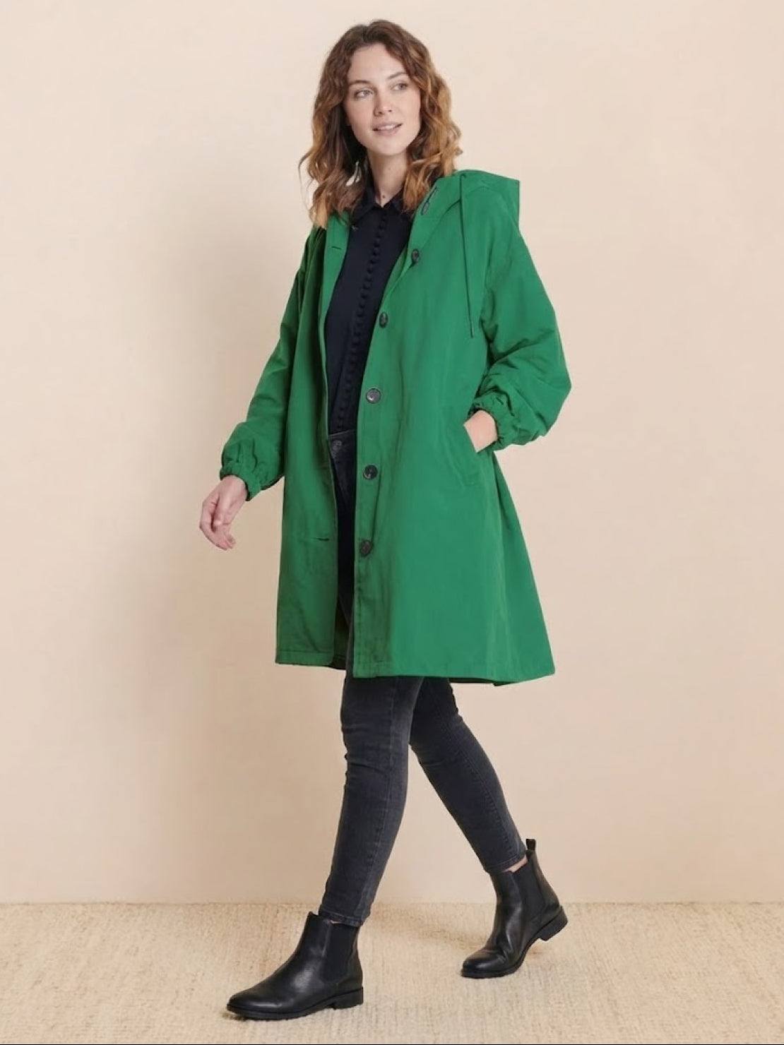 Woman wearing green Rain Couture Windbreaker oversized water-resistant jacket with hood and pockets