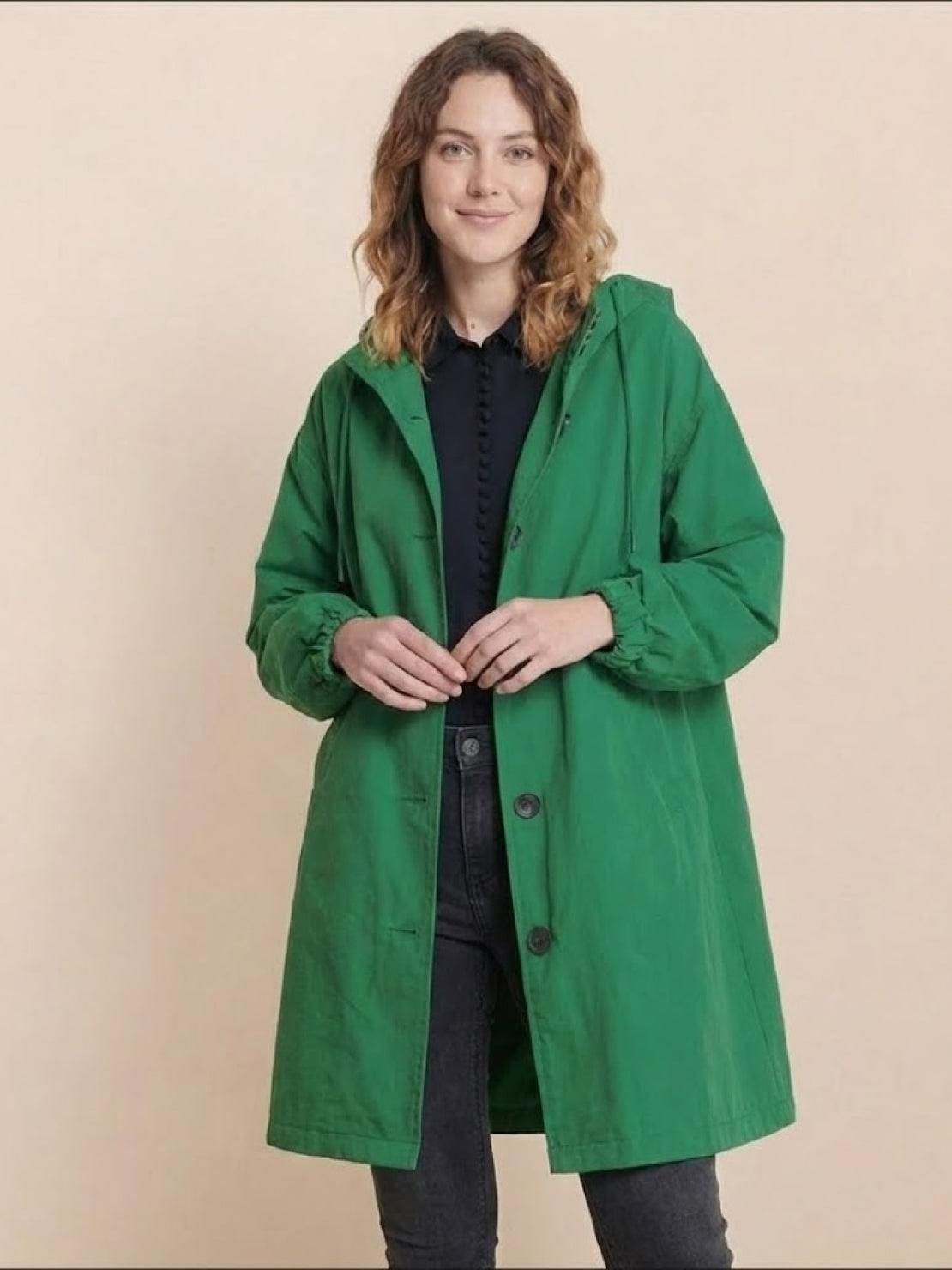 Woman wearing oversized green Rain Couture Windbreaker water-resistant jacket with hood and buttons