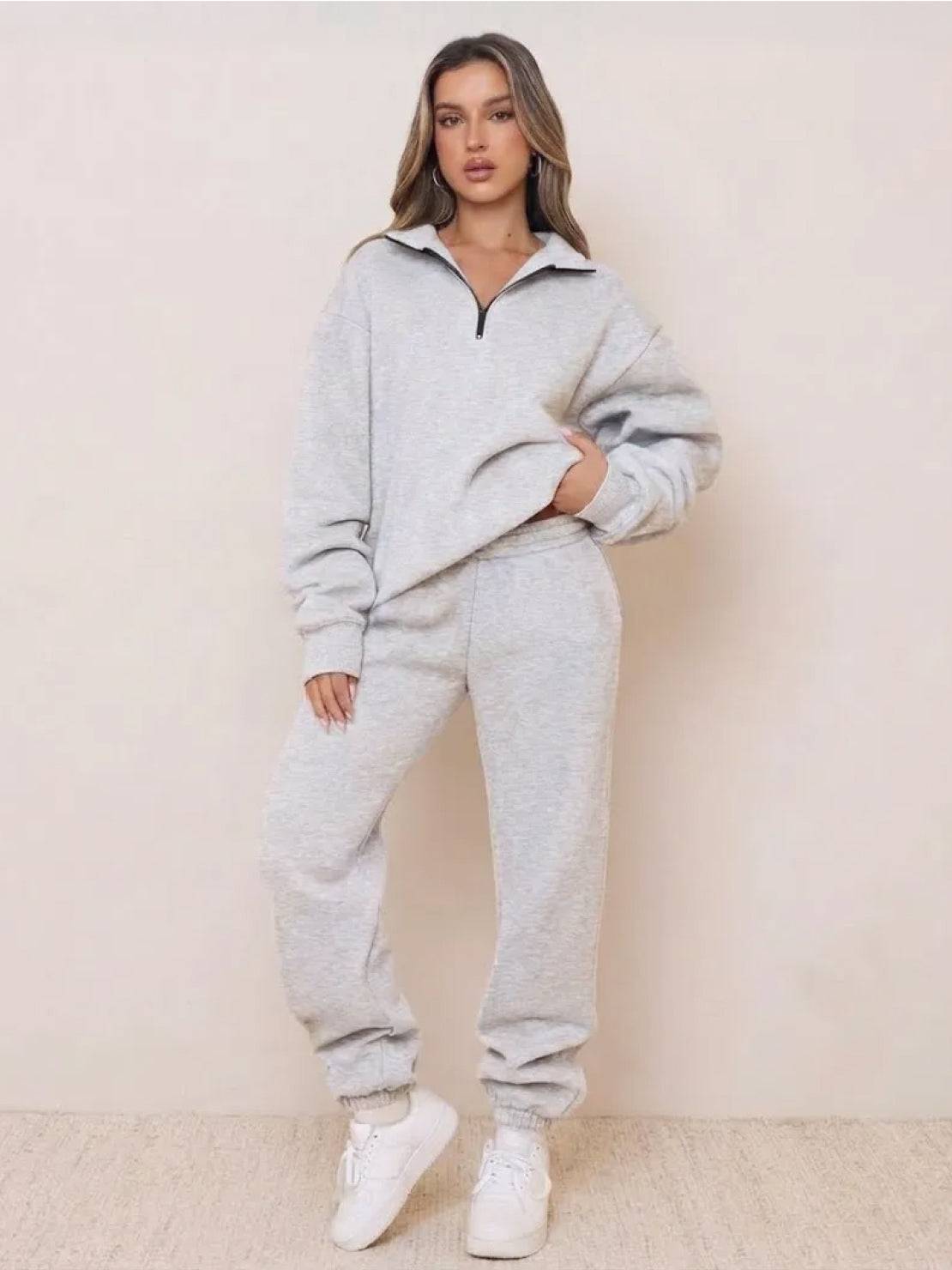 Woman wearing gray ultra-soft and comfy co-ord tracksuit set with zip-up top and jogger pants, paired with white sneakers