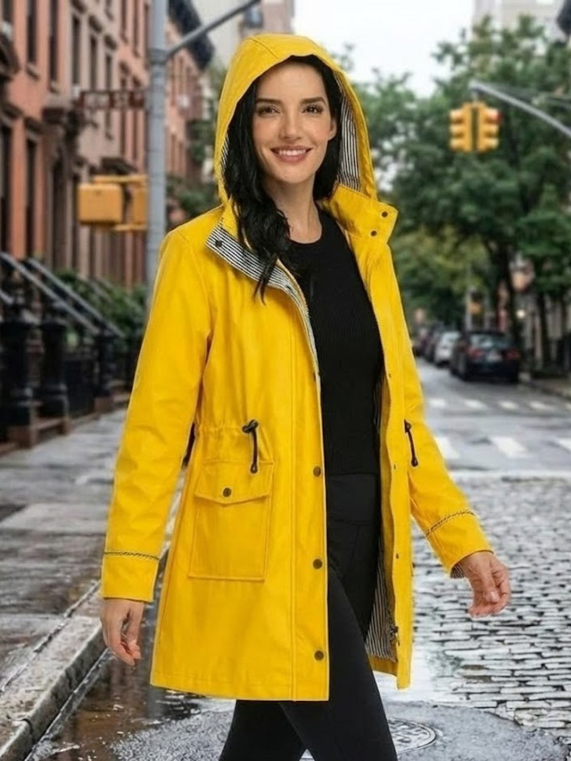 woman wearing yellow water resistant hooded striped windbreaker jacket on city street