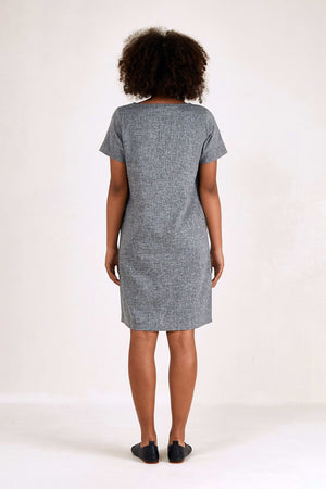 Back view of woman wearing grey short sleeve shift dress with side pockets and knee-length hem