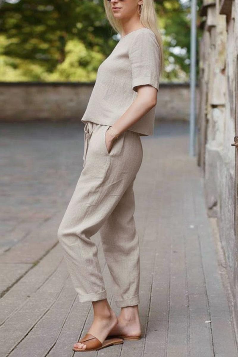 Woman wearing beige cotton linen set with relaxed short-sleeve top and straight-leg pants outdoors