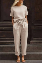 Woman wearing beige cotton linen set with short-sleeve top and straight-leg pants with drawstring waist