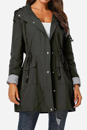 Woman wearing black water resistant windbreaker jacket with hood and striped cuffs