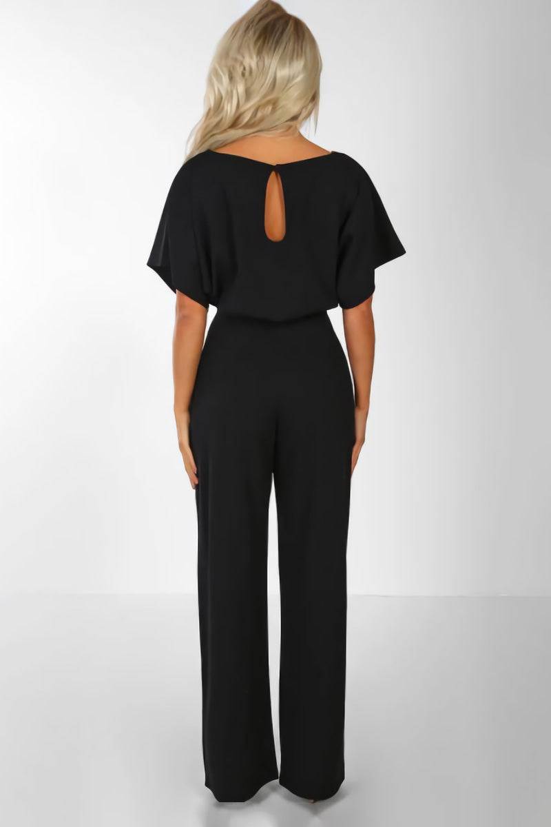 Woman wearing a black chic short-sleeved wide-leg jumpsuit with back keyhole detail and belt.