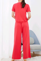 Woman wearing red bamboo fiber pajama clothes with short sleeves and wide-leg pants in a modern room.