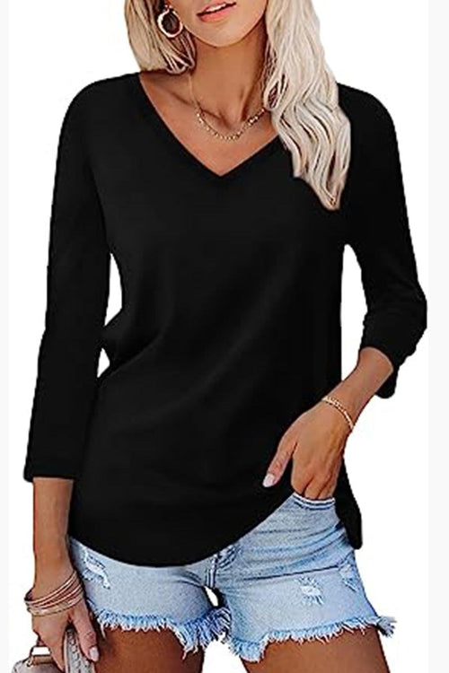 Woman wearing black V-neck top and distressed denim shorts with hand in pocket