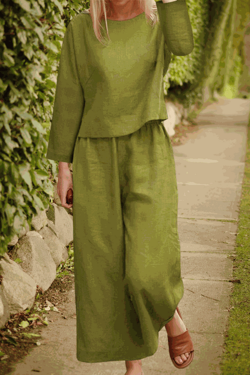 Woman wearing loose solid color olive green two-piece set with long sleeves and wide-leg pants outdoors
