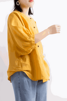 Relaxed loose breathable linen blouse in bright yellow with button-down front and 3/4 puff sleeves worn with blue jeans