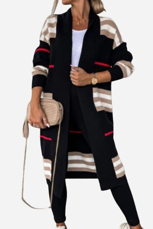 Woman wearing cozy striped long knitted cardigan with oversized fit and long silhouette in black, beige, and red stripes