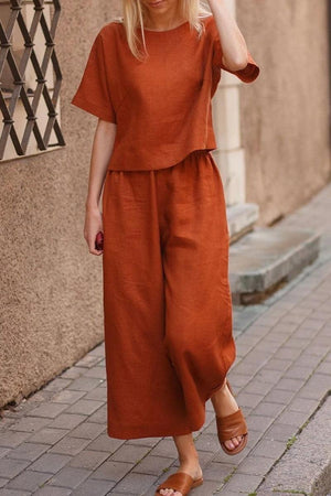 Woman wearing rust-colored loose fit co-ord set with wide-leg trousers and short-sleeve top outdoors