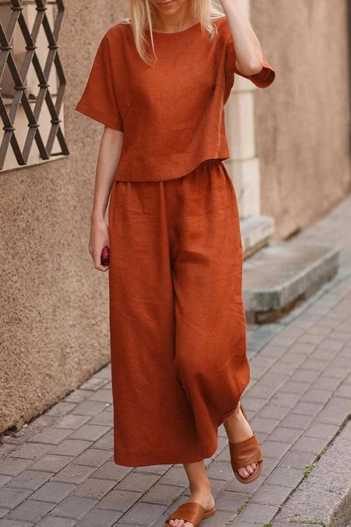 Woman wearing rust-colored loose fit co-ord set with wide-leg trousers and short-sleeve top outdoors
