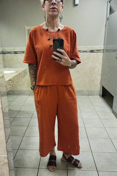 Woman wearing rust-orange loose fit co-ord set with short wide sleeves and wide-leg pants in a restroom mirror selfie