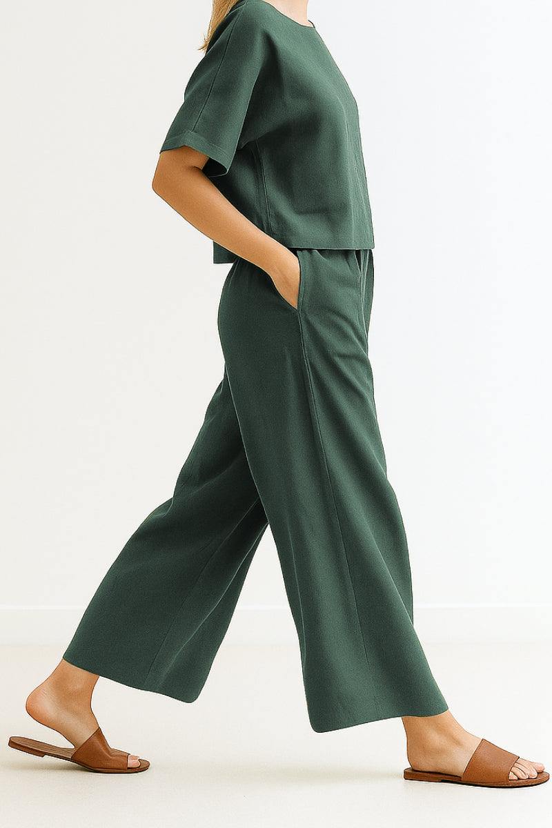 Woman wearing dark green loose fit co-ord set with short-sleeve top and wide-leg pants paired with brown sandals