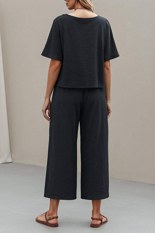 Back view of a woman wearing a black loose fit co-ord set with wide-leg pants and relaxed short-sleeve top.