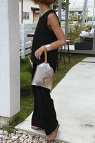 Loose solid color sleeveless two-piece set with oversized fit and wide-leg pants in black worn outdoors