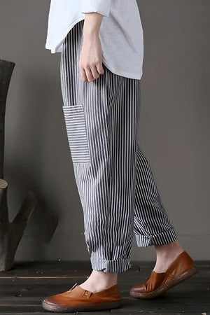 Woman wearing high waist striped black and white comfort pants with side pocket and rolled cuffs.