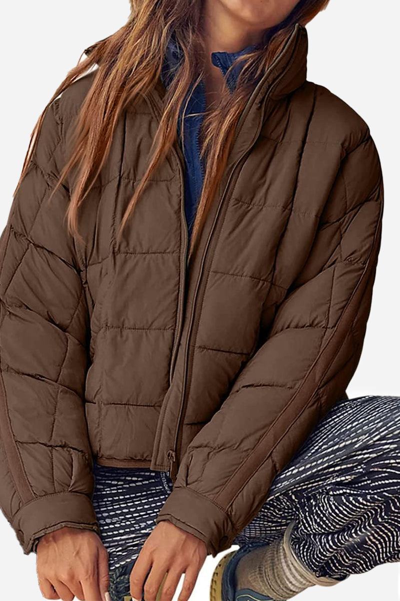 Brown lightweight puffer travel jacket on woman with relaxed fit and high collar