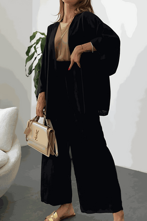 Woman wearing black Chic Comfort Kimono two-piece set with beige top and beige handbag, indoor setting