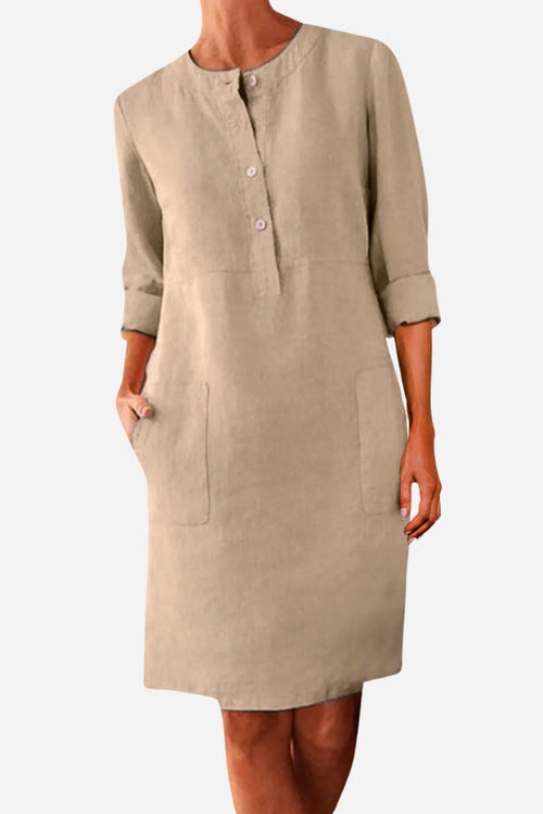 Khaki cotton dress with 3/4 rolled sleeves, front buttons, and pockets, casual knee-length style.