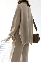 Woman wearing beige high neck sweater with wide leg pants set carrying brown shoulder bag, cozy and stylish outfit.