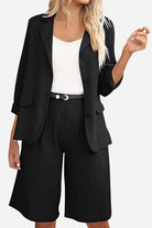 Black blazer and high-waisted shorts two-piece set with a white top, featuring a tailored fit and rolled-up sleeves.