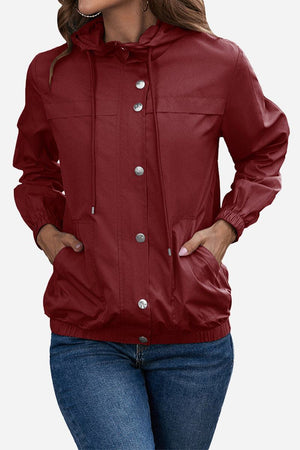 Women's outdoor hooded raincoat and windbreaker in red with button closure and elastic cuffs.