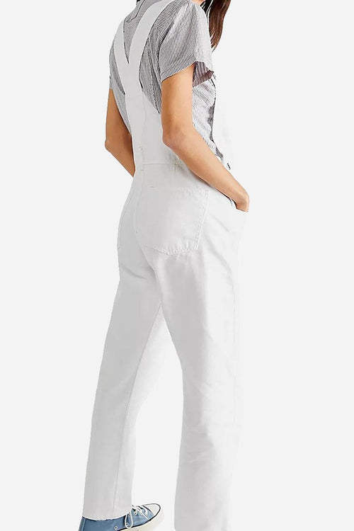 White denim-look tapered-leg adjustable bib overalls with pockets worn by woman viewed from back