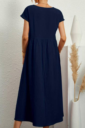 Back view of navy blue capped-sleeve voluminous pleated midi dress with relaxed fit and flowing skirt