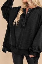 Black oversized urban sweatshirt with buttoned Henley neckline and slouchy sleeves worn by blonde woman