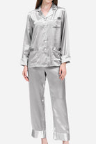 Woman wearing silver long sleeve silk pajamas set with button-up top and matching pants