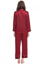 back view of woman wearing long sleeve silk pajamas set in deep red mulberry silk with button-up top and matching pants