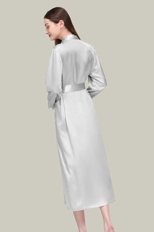 Woman wearing elegant white Mulberry silk nightgown with sash belt and long sleeves, back view