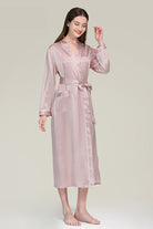 Woman wearing pink Mulberry silk nightgown with long sleeves and sash belt against neutral background