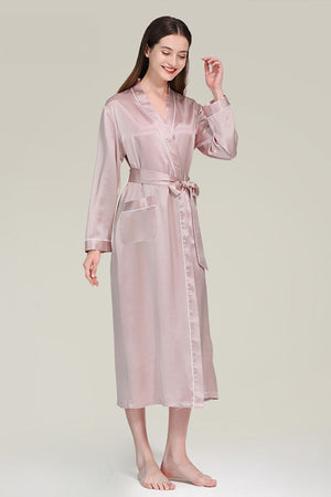 Woman wearing pink Mulberry silk nightgown with long sleeves and sash belt against neutral background