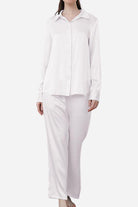 Woman wearing classic white Mulberry silk sleepwear set with long sleeves and full-length pants