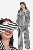 Woman wearing 100% mulberry silk black and white striped long sleeve pajama set with matching headband and eye mask