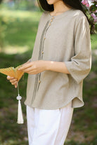 Woman wearing beige linen cotton classy eco-friendly shirt with button details and white pants outdoors