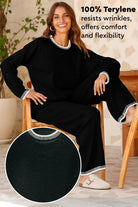 Woman wearing Chic Contrast Stitch black travel set with white stitching, made of wrinkle-resistant 100% terylene fabric, sitting on chair.