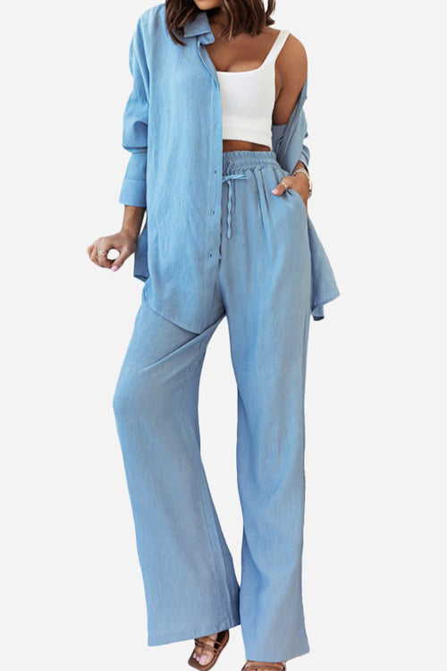 Woman wearing a light blue professional two-piece set with loose pants and matching button-up shirt, styled with a white crop top.