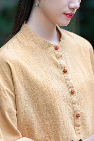 Woman wearing a beige ramie linen and cotton blouse with a stand collar and wooden buttons