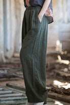Side view of relaxed fit dark green sandwashed ramie linen pants with elastic waistband and pockets