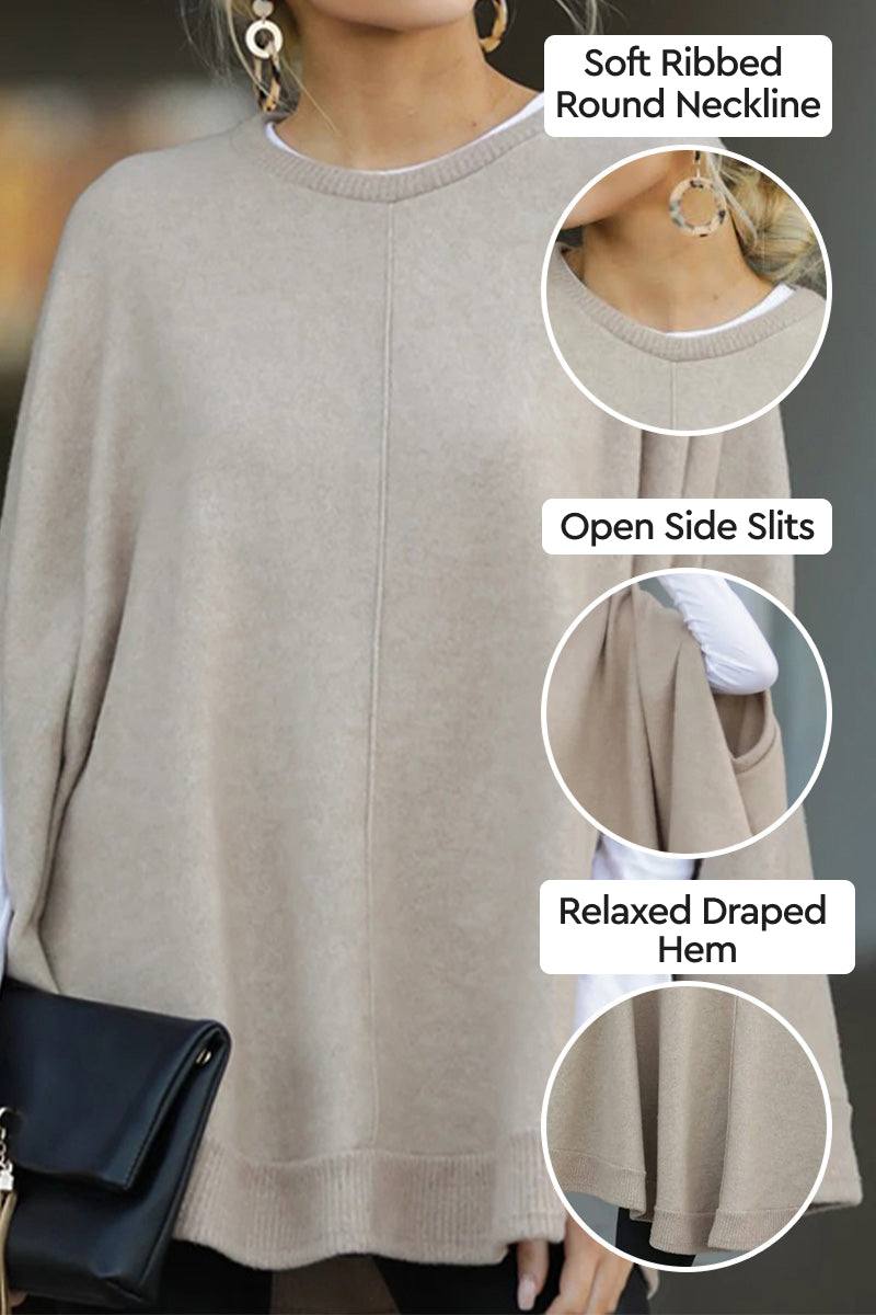 Elegant poncho pullover in light beige with soft ribbed round neckline, open side slits, and relaxed draped hem, styled with gold hoop earrings and black clutch bag.