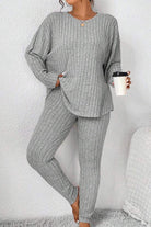 Woman wearing a gray Body Confident Oversized Knit two-piece set holding a coffee cup against a white wall background