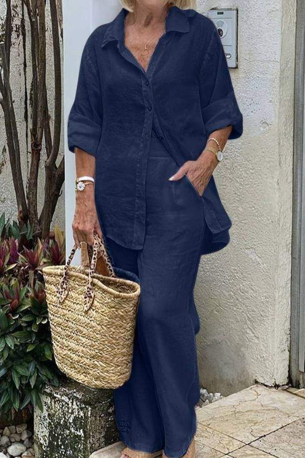 Woman wearing navy blue Casual Chic Duo relaxed shirt and trousers set with a woven straw bag outdoors